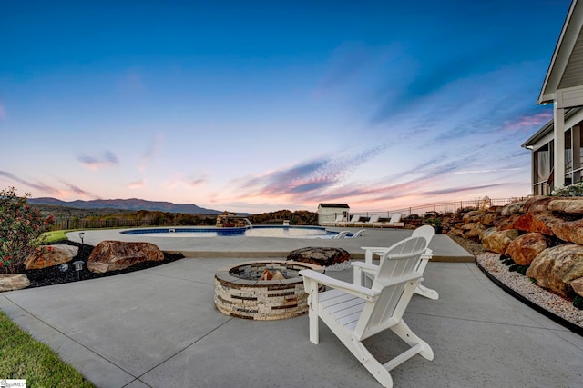 patio terrace at dusk featuring a fire pit and a mountain view