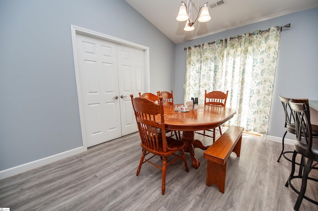 dining space with a chandelier, light hardwood / wood-style floors, and lofted ceiling