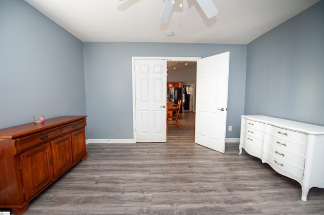 bedroom with ceiling fan, hardwood / wood-style floors, and stainless steel refrigerator with ice dispenser