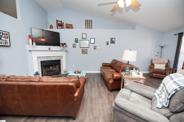 living room with ceiling fan, a high end fireplace, wood-type flooring, and vaulted ceiling