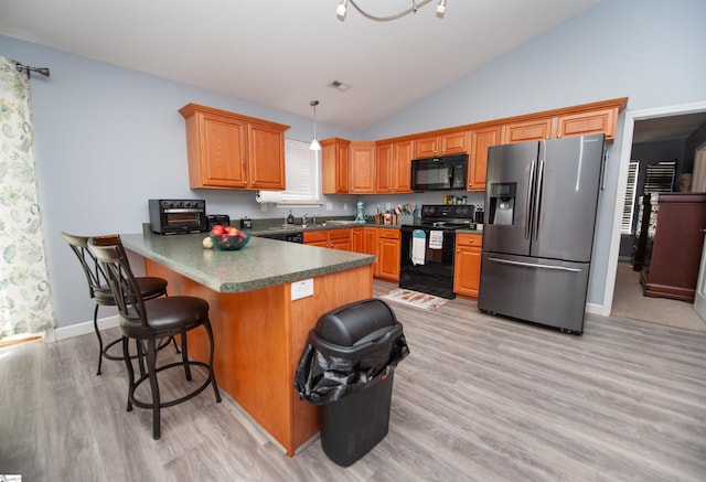 kitchen featuring kitchen peninsula, light hardwood / wood-style floors, lofted ceiling, decorative light fixtures, and black appliances