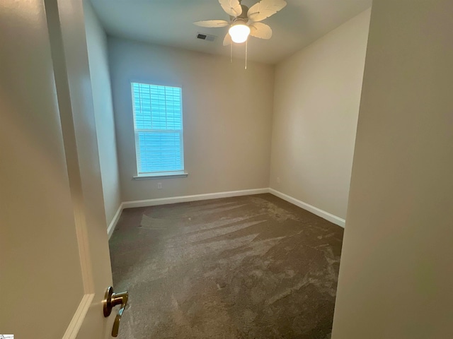 empty room with dark colored carpet and ceiling fan