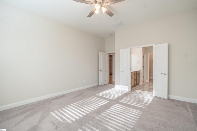 unfurnished bedroom featuring light carpet, ensuite bathroom, high vaulted ceiling, and ceiling fan