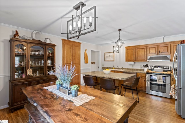 dining area with crown molding, hardwood / wood-style floors, and an inviting chandelier