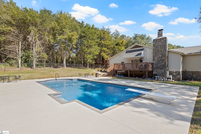 view of swimming pool with a diving board, a patio area, a deck, and a yard