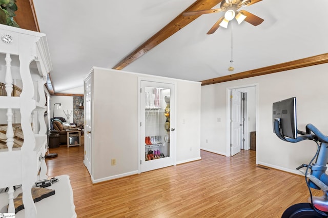 workout area featuring ceiling fan, light hardwood / wood-style floors, and vaulted ceiling