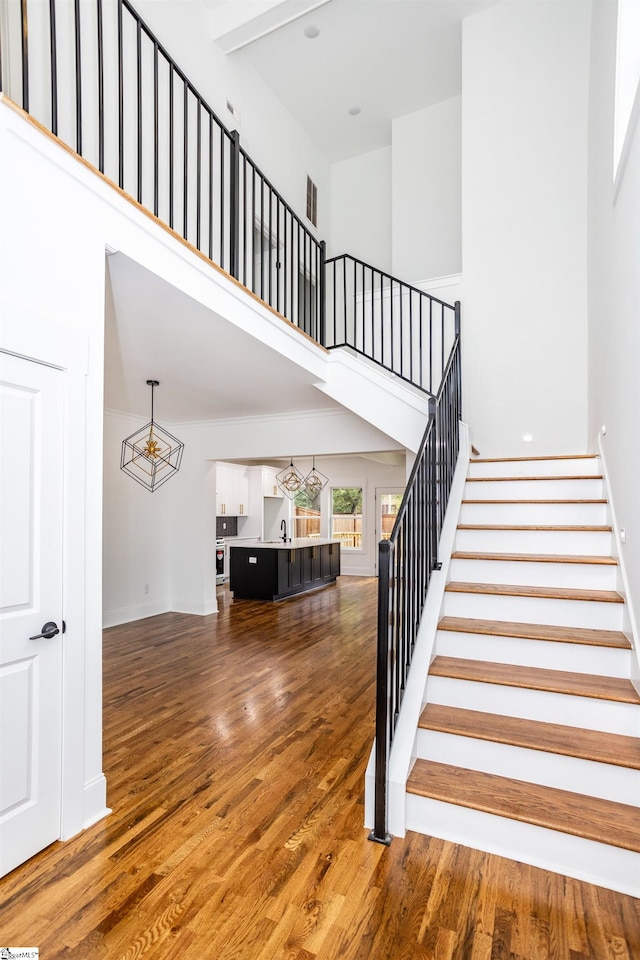 stairway with a high ceiling and hardwood / wood-style flooring