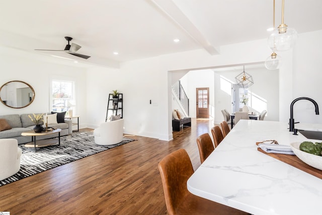 dining space with beamed ceiling, ceiling fan, dark wood-type flooring, and sink