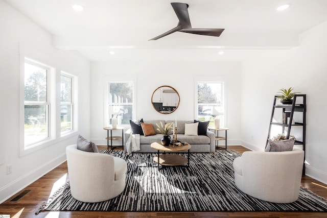 living room featuring ceiling fan, dark hardwood / wood-style flooring, beamed ceiling, and a healthy amount of sunlight