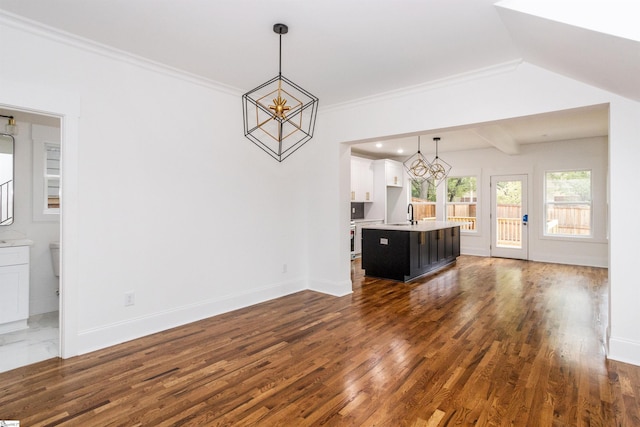 unfurnished living room featuring ornamental molding, dark hardwood / wood-style flooring, a notable chandelier, and sink