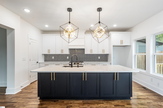 kitchen with pendant lighting, a center island with sink, hardwood / wood-style flooring, tasteful backsplash, and white cabinetry