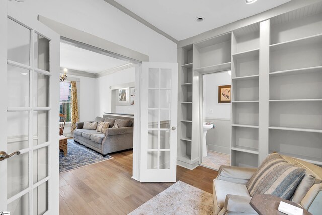 sitting room featuring hardwood / wood-style floors, built in shelves, ornamental molding, and french doors