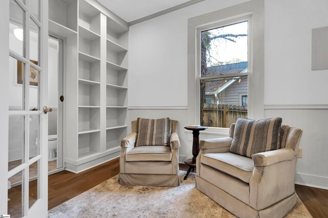 living area featuring built in shelves and hardwood / wood-style floors