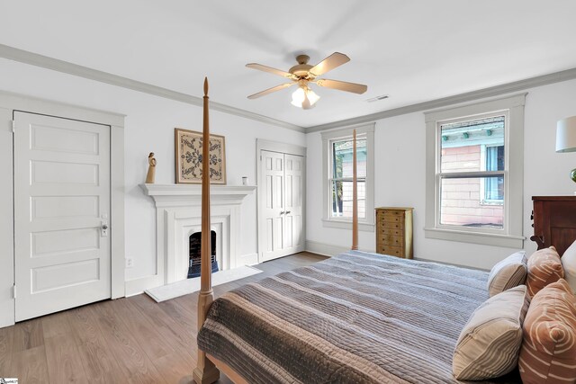 bedroom with wood-type flooring, a closet, ceiling fan, and ornamental molding