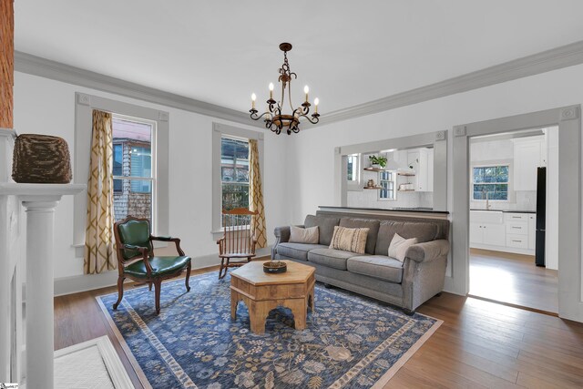 living room with hardwood / wood-style flooring, crown molding, and an inviting chandelier