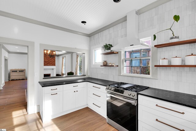 kitchen featuring extractor fan, stainless steel range with gas stovetop, decorative backsplash, and white cabinetry