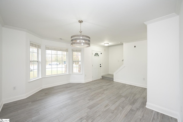 empty room featuring ornamental molding, wood-type flooring, and a notable chandelier