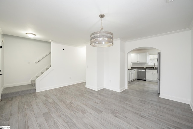 unfurnished living room with light hardwood / wood-style floors, crown molding, and a notable chandelier