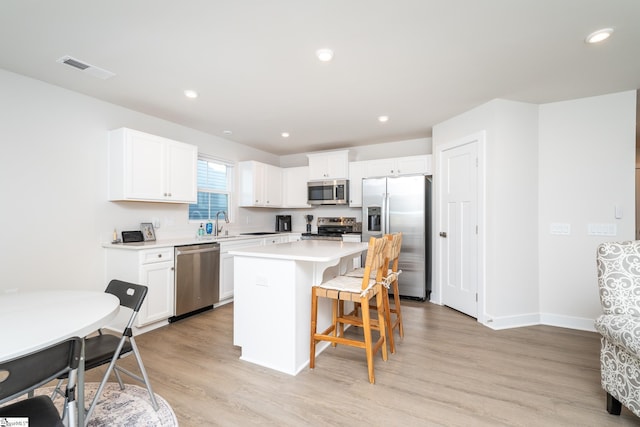 kitchen with a breakfast bar, light hardwood / wood-style flooring, a kitchen island, and stainless steel appliances