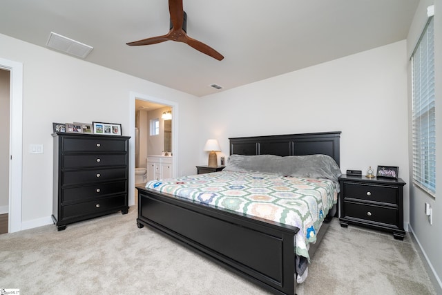 bedroom featuring ensuite bath, ceiling fan, and light carpet