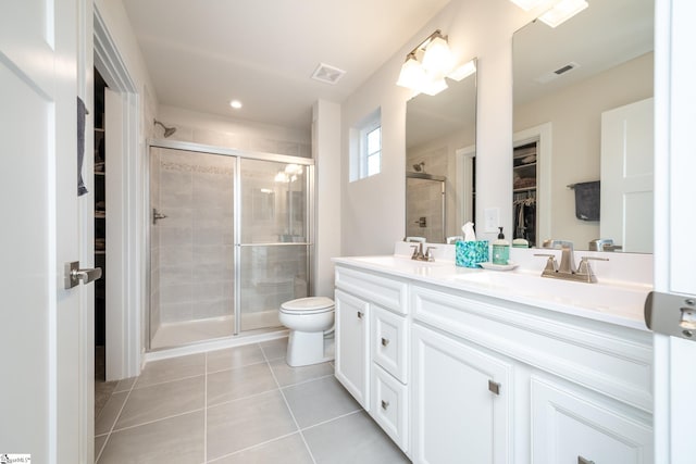 bathroom featuring toilet, vanity, tile patterned floors, and a shower with shower door