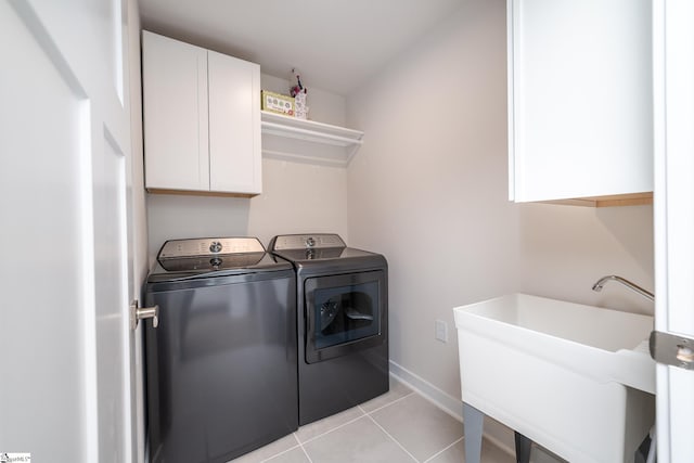 laundry area with washing machine and dryer, sink, light tile patterned floors, and cabinets