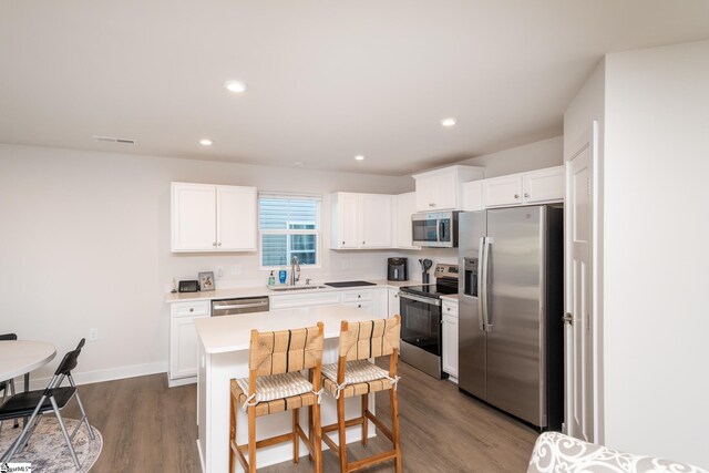 kitchen with sink, a kitchen island, dark hardwood / wood-style flooring, white cabinetry, and stainless steel appliances