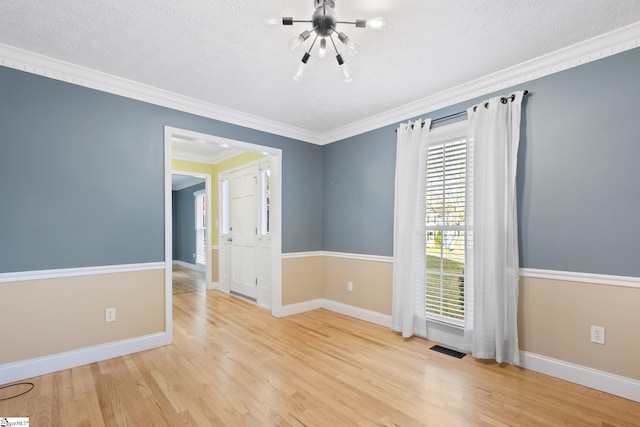 empty room with light hardwood / wood-style floors, ornamental molding, and a textured ceiling