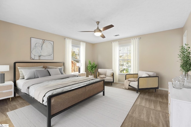 carpeted bedroom featuring ceiling fan and multiple windows