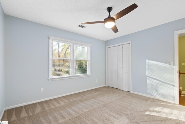 unfurnished bedroom featuring light carpet, a closet, and ceiling fan