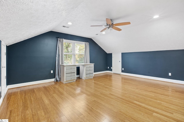 additional living space with lofted ceiling, light hardwood / wood-style flooring, ceiling fan, and a textured ceiling