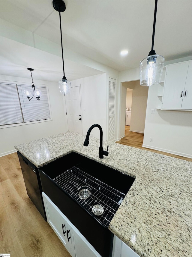 kitchen with light wood-type flooring, decorative light fixtures, white cabinetry, and light stone counters