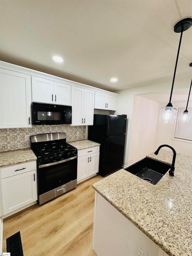 kitchen with pendant lighting, backsplash, black appliances, light hardwood / wood-style flooring, and white cabinetry