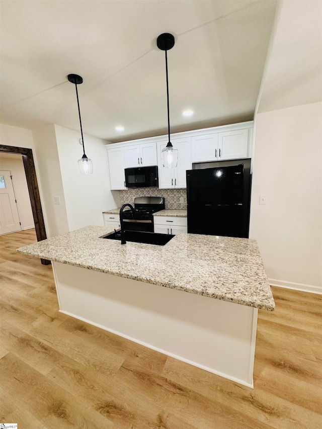 kitchen featuring backsplash, black appliances, light wood-type flooring, decorative light fixtures, and white cabinetry