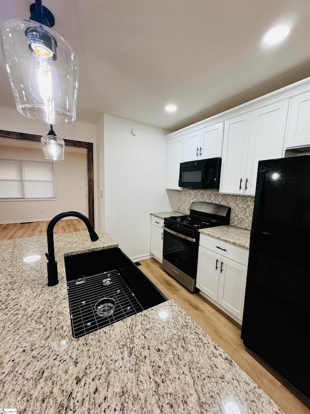 kitchen featuring white cabinets, light hardwood / wood-style flooring, and black appliances