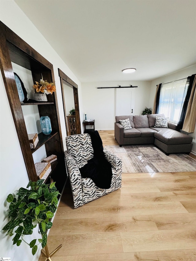 living room with a barn door and light hardwood / wood-style floors