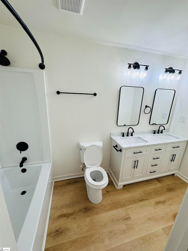 full bathroom featuring hardwood / wood-style floors, vanity, toilet, and bathtub / shower combination