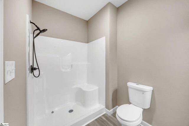 bathroom featuring hardwood / wood-style floors, toilet, and walk in shower