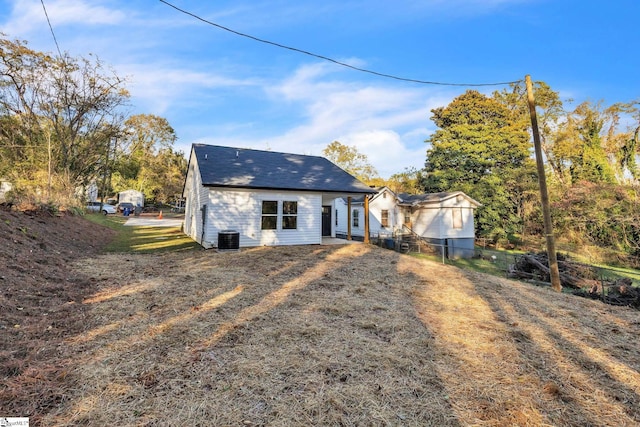 back of property with a lawn and central AC