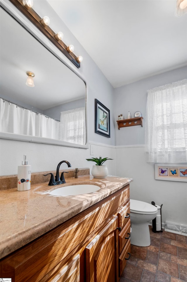 bathroom with vanity, toilet, and a wealth of natural light