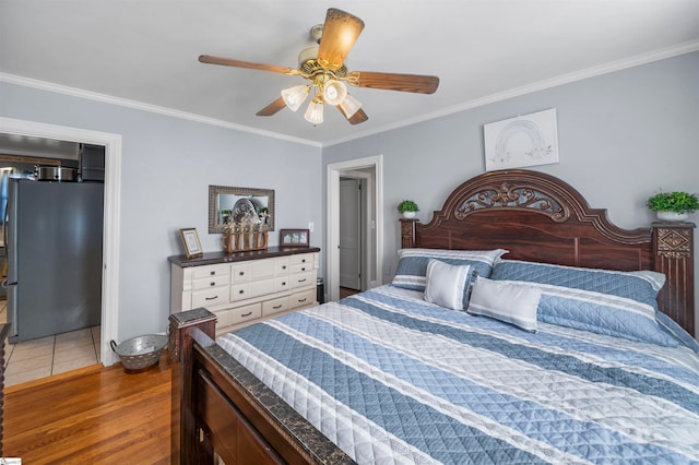 bedroom featuring wood-type flooring, stainless steel refrigerator, ceiling fan, and ornamental molding