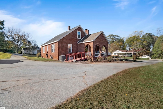 front facade with central air condition unit, covered porch, and a front yard