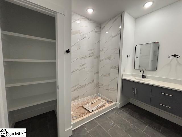 full bathroom featuring recessed lighting, vanity, and a marble finish shower