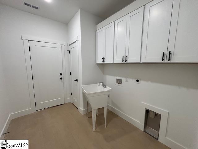 washroom with cabinet space, visible vents, light wood-style floors, washer hookup, and electric dryer hookup