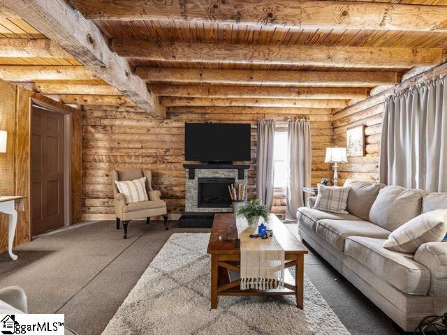 living room featuring log walls, a fireplace, beamed ceiling, and wood ceiling