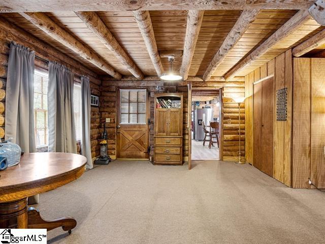 unfurnished room featuring beamed ceiling, light colored carpet, and wood ceiling