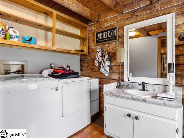 laundry room with independent washer and dryer, light hardwood / wood-style floors, and sink