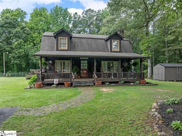 view of front of home with covered porch, a front yard, and a storage shed