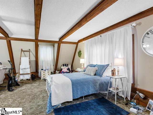 bedroom with carpet flooring, beamed ceiling, and a textured ceiling