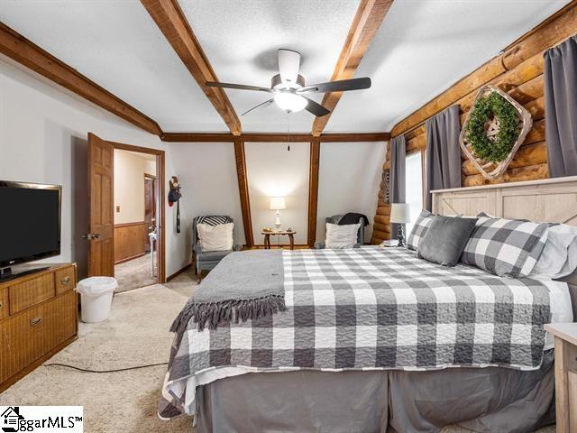 carpeted bedroom featuring beamed ceiling and ceiling fan